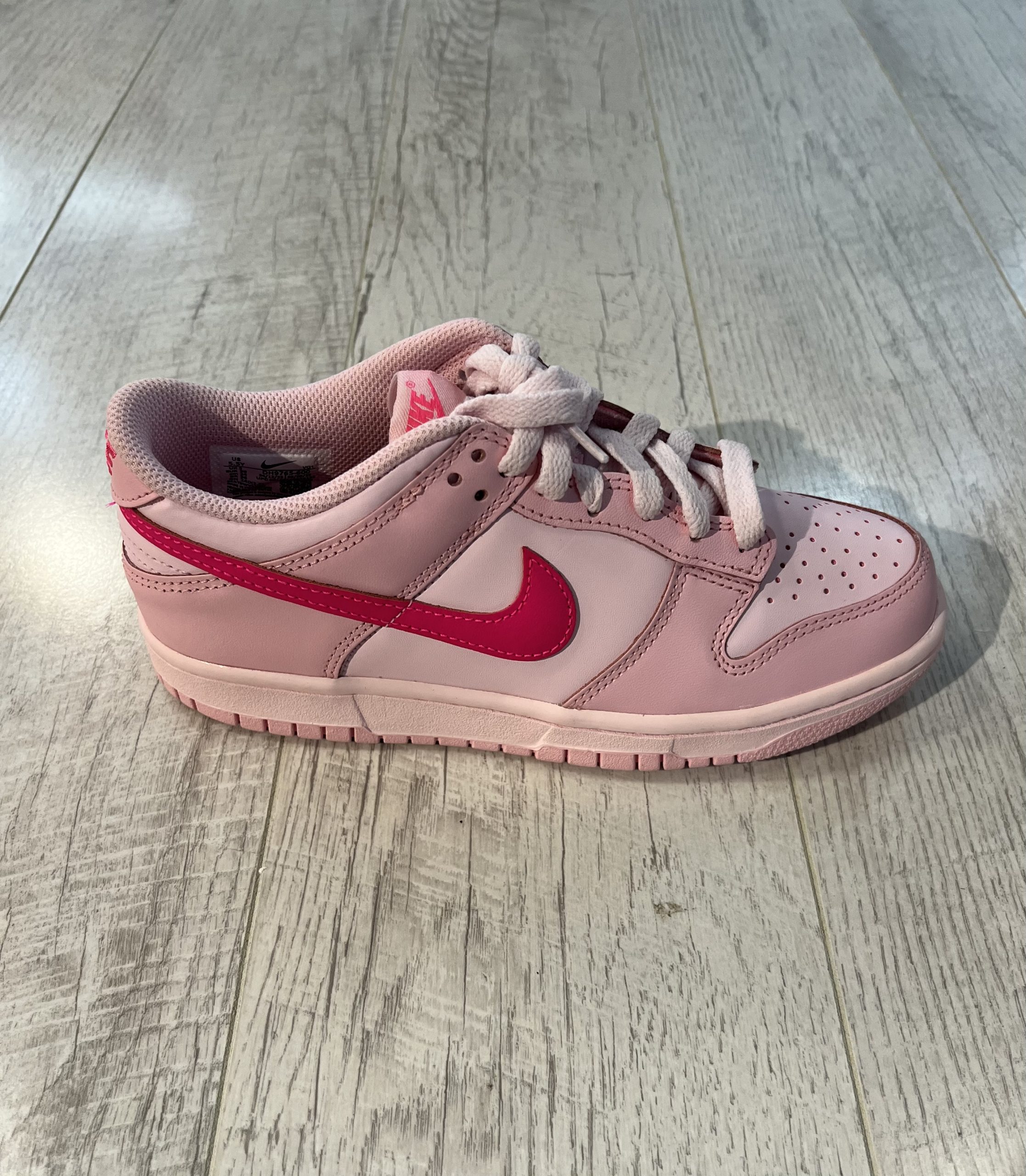 nike-dunk-low-triple-pink.jpeg Vu de coté de la paire de Nike dunk low triple pink. Différentes teintes de rose. Un. logo nike rose foncé. Des lacets rose clair.
