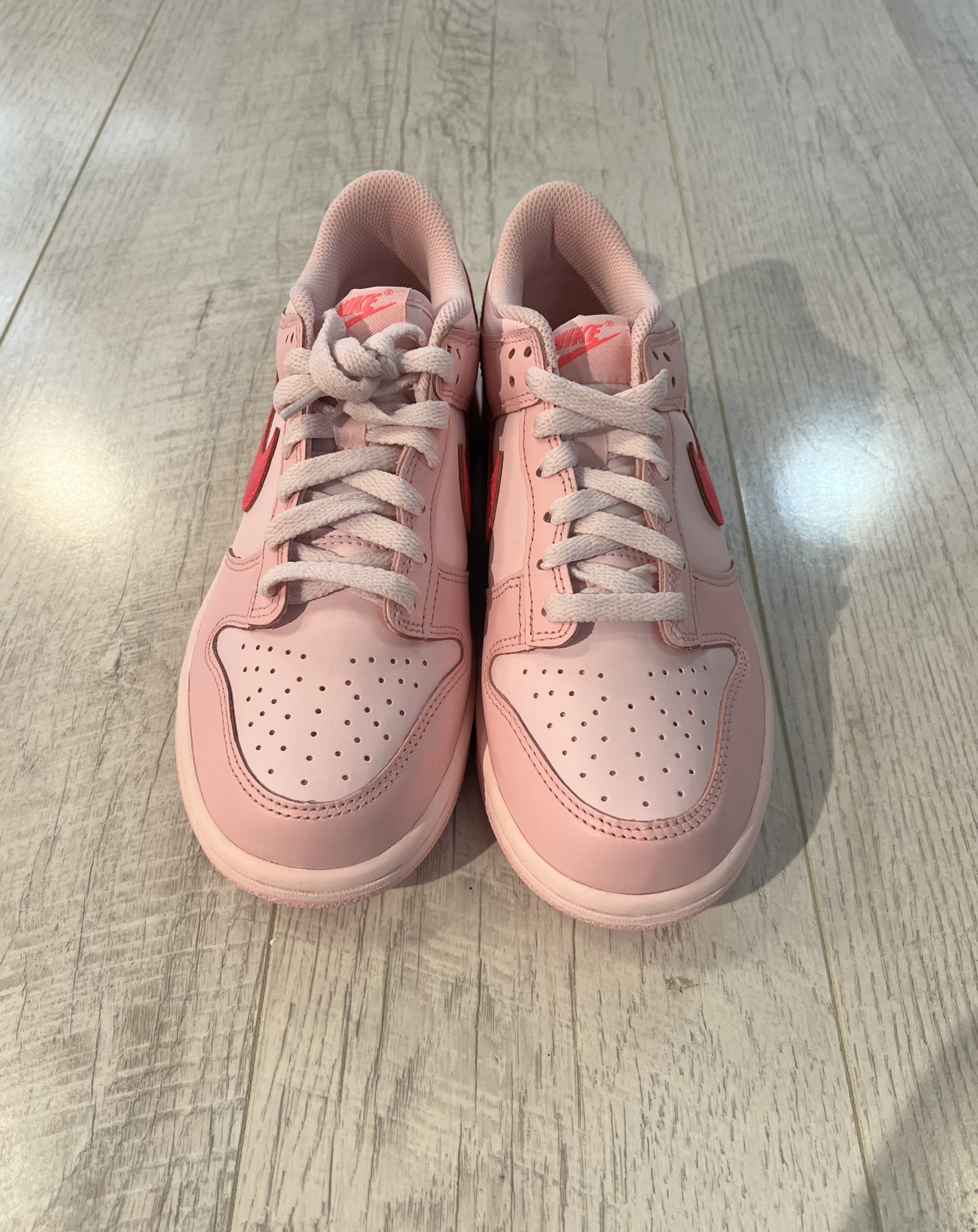 nike-dunk-low-triple-pink.jpeg Vu du dessus de la paire de Nike dunk low triple pink. Différentes teintes de rose. Des lacets rose clair.
