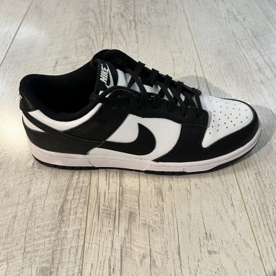 Vu de coté de la Nike dunk low panda. La couleur noire domine la paire avec du blanc. Des lacets noirs.
