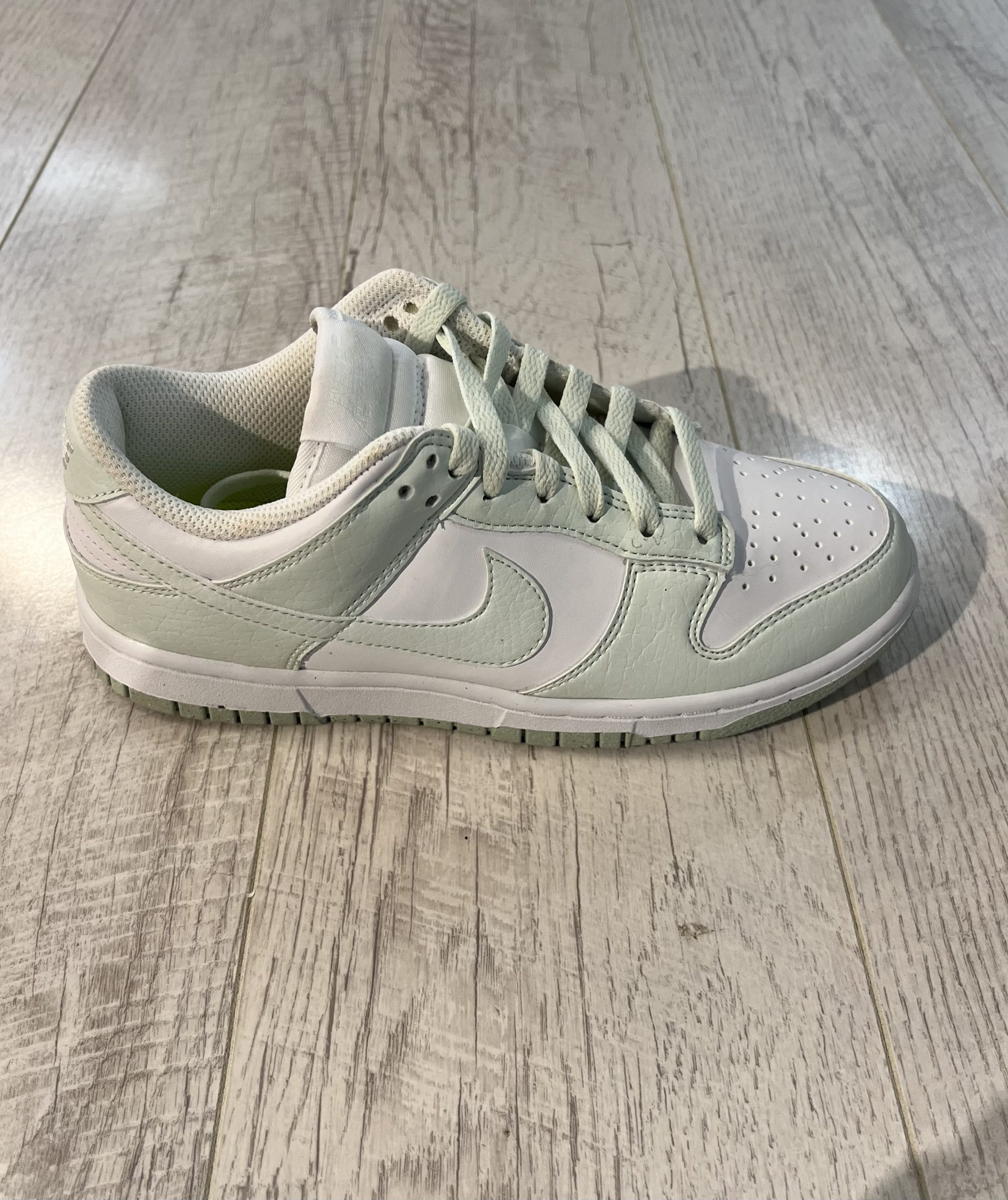 nike-dunk-low-next-nature-white-mint.jpeg Vu de coté de la Nike dunk low next nature white mint. Une couleur vert pastel domine la paire avec du blanc. Des lacets couleur pastel.