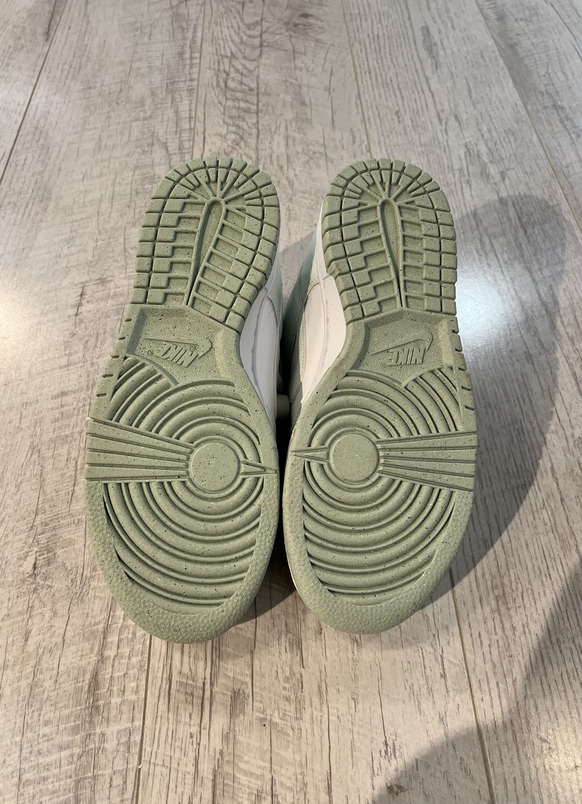 nike-dunk-low-next-nature-white-mint.jpeg Vu du dessous de la Nike dunk low next nature white mint. Une couleur vert pastel domine la semelle de la paire.