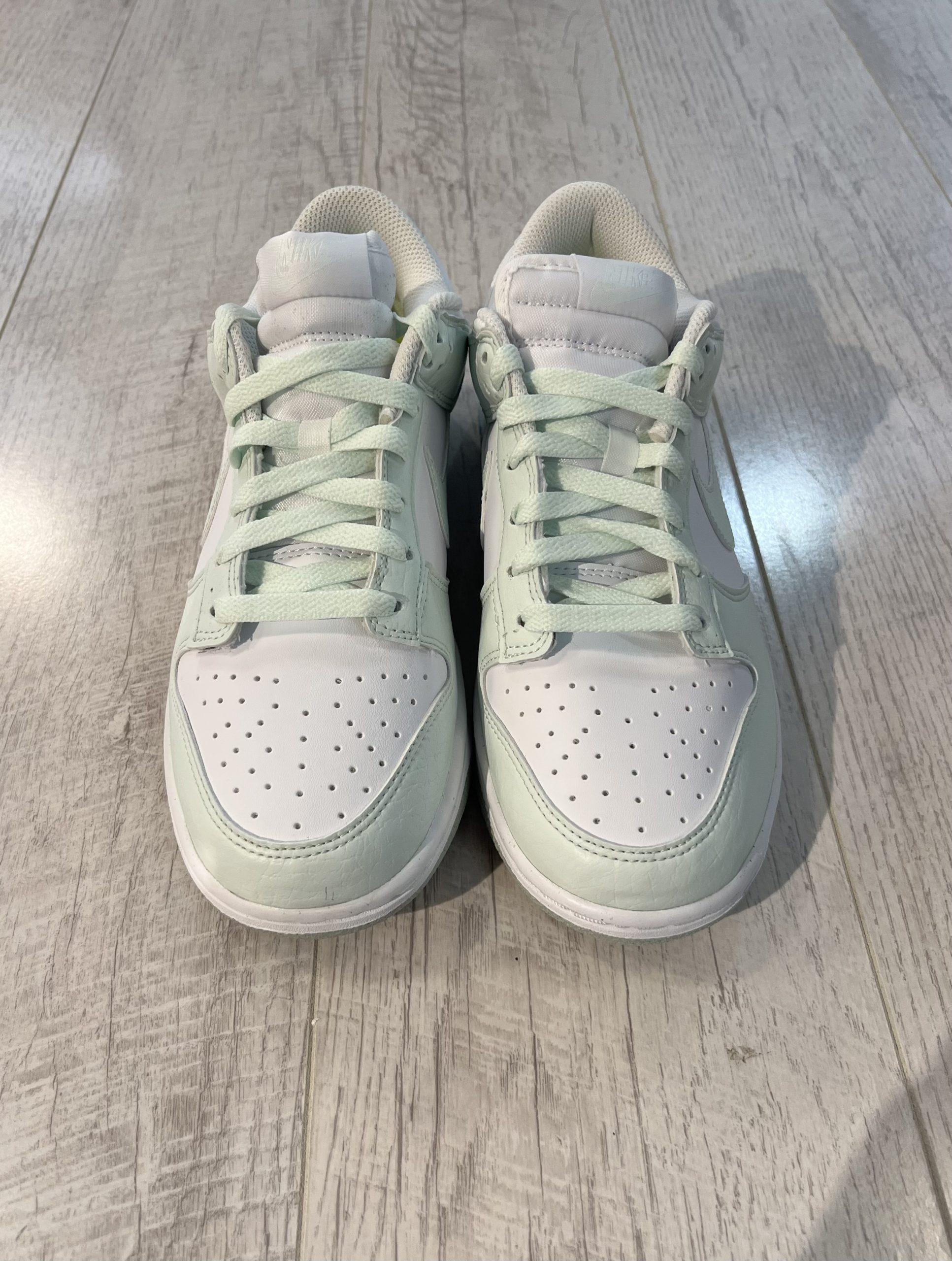 nike-dunk-low-next-nature-white-mint.jpeg Vu du dessus de la Nike dunk low next nature white mint. Une couleur vert pastel domine la paire avec du blanc. Des lacets couleur pastel.