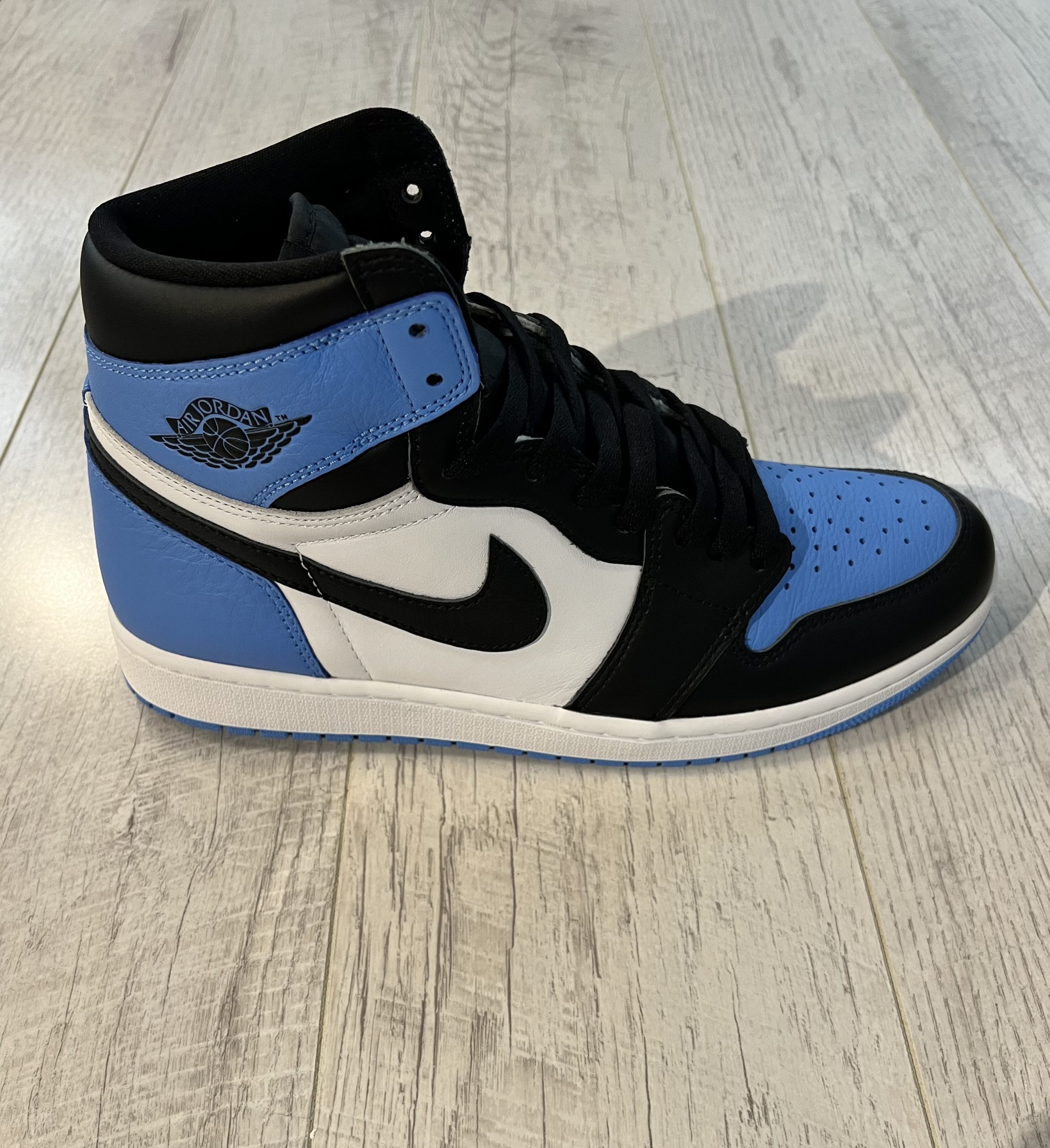 nike-air-jordan-1-high-og-university-blue-unc-toe.jpeg Vu de coté de la Nike Air Jordan 1 High OG University Blue UNC Toe. Du bleu et du noir ainsi que du blanc. Un swoosh nike noir. Des lacets noirs.