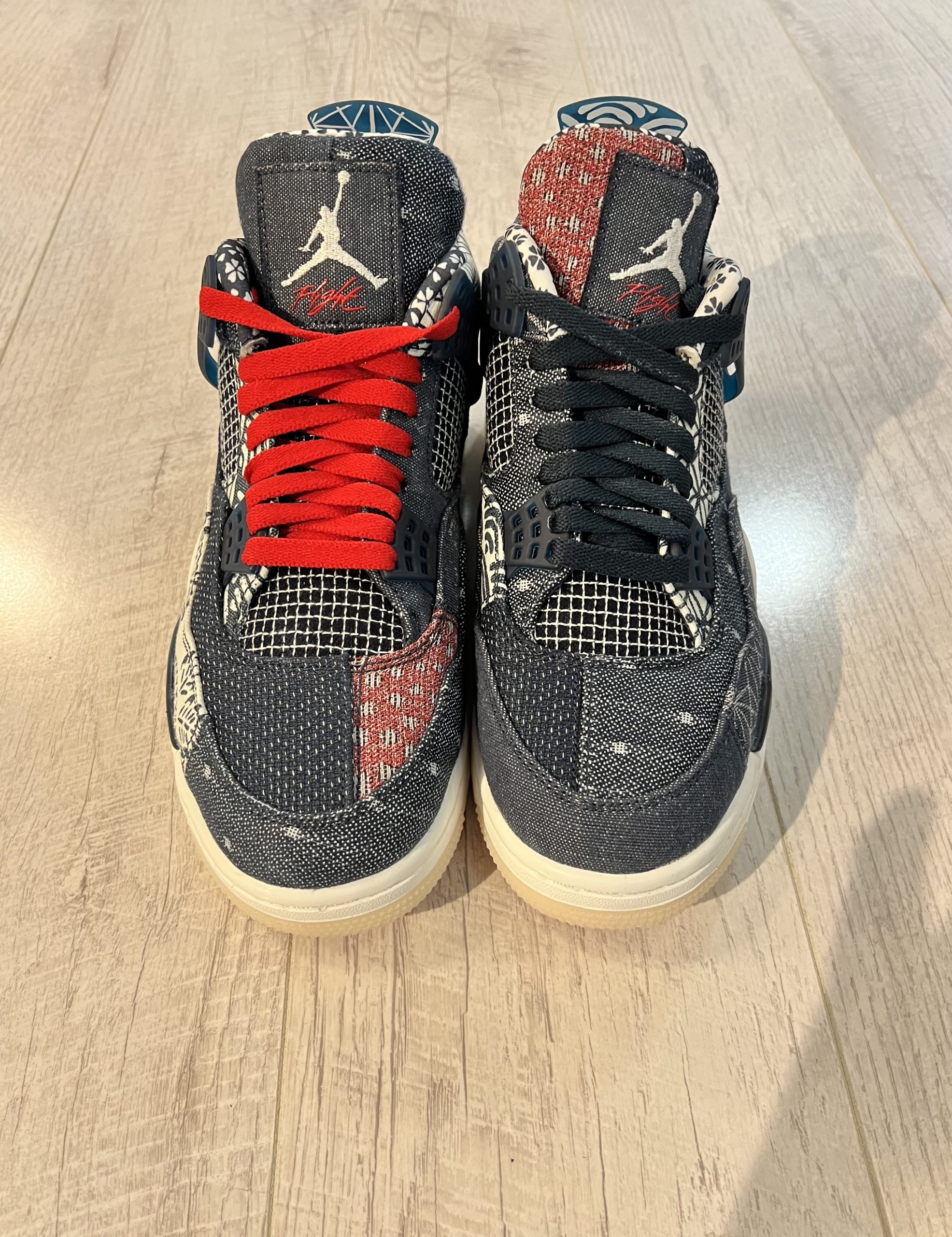 nike-jordan-4-se-deep-ocean.jpeg Vu du dessus de la paire de Nike Jordan 4 SE Deep Ocean. Une couleur effet jeans est presente de couleur bleu avec quelques touches de rouges Des lacets rouges sur la chaussure droite et des noirs sur la gauche. Une semelle blanche.