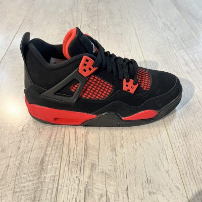 Vu de coté de la Nike Air Jordan 4 Red Thunder. Du noir et du rouge sur la paire. Un logo jordan blanc sur la languette.