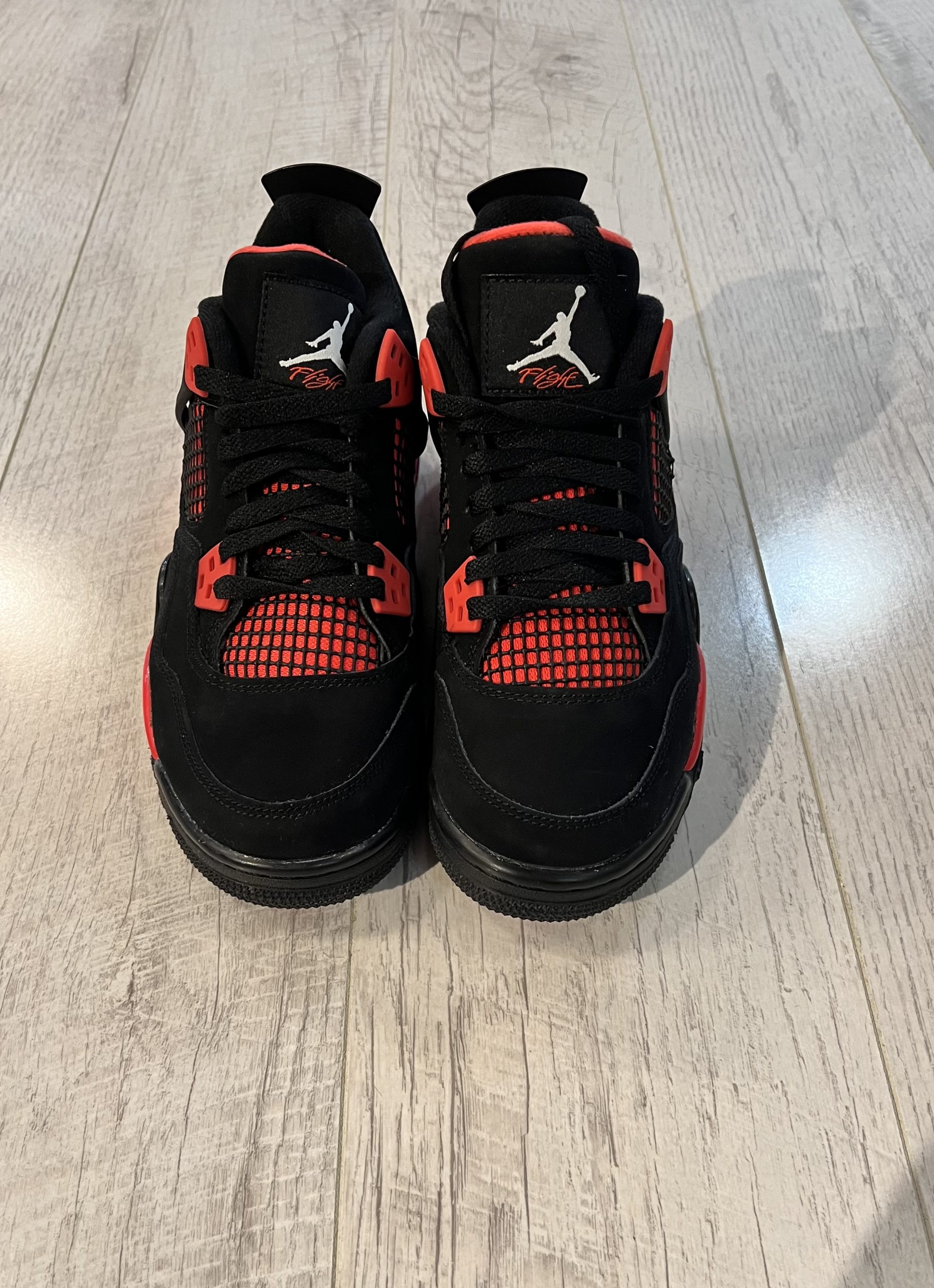 nike-air-jordan-4-red-thunder.jpeg Vu du dessus de la Nike Air Jordan 4 Red Thunder. Du noir et du rouge sur la paire. Un logo jordan blanc sur la languette.