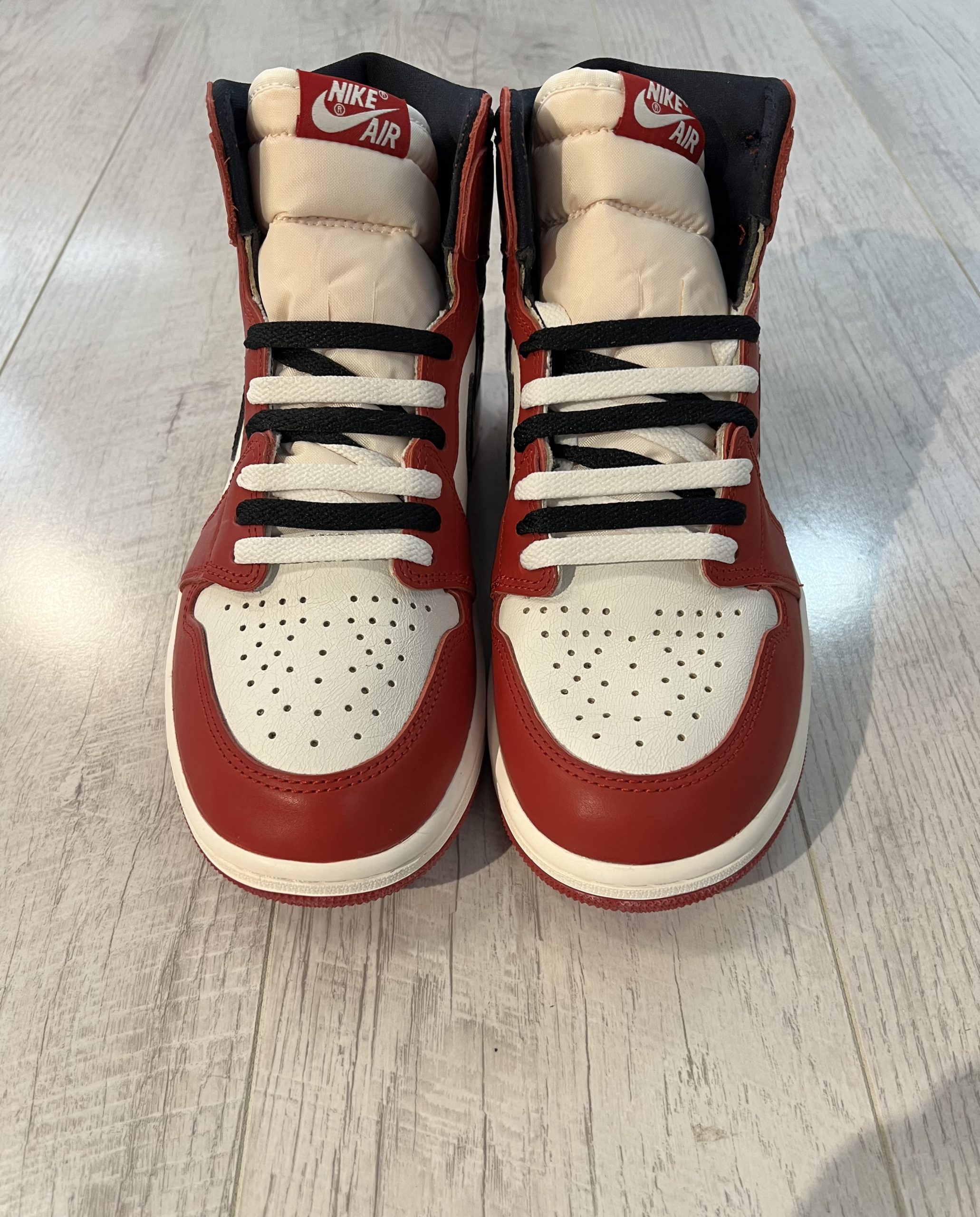 nike-air-jordan-1-high-og-lost-and-found.jpeg Vu du dessus de la Nike Air Jordan 1 High OG Lost and Found. Le rouge et le blanc dominent. Une languette beige et des lacets noirs et blancs. L'intérieur de la paire est noir.
