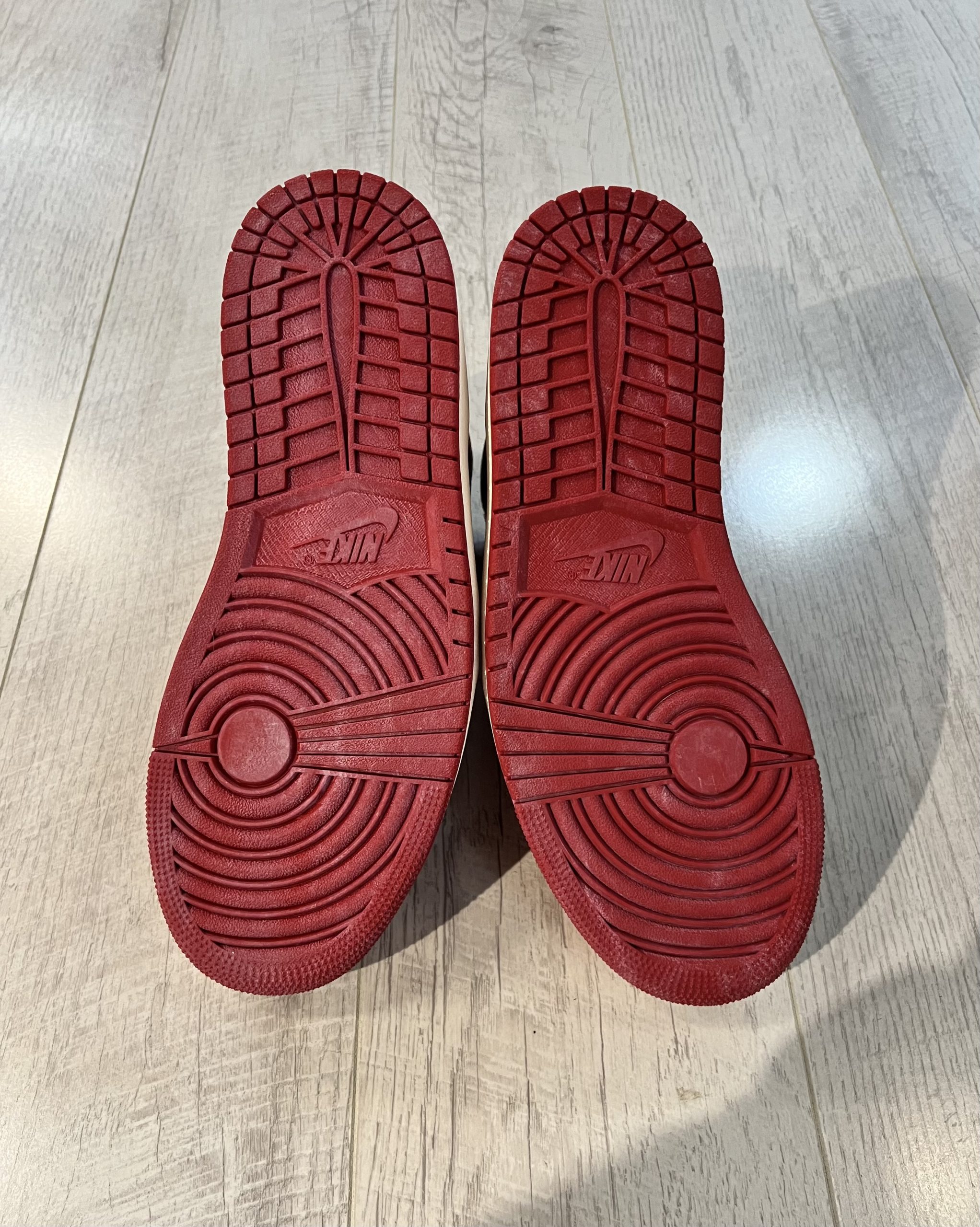 nike-air-jordan-1-high-og-lost-and-found.jpeg Vu du dessous de la Nike Air Jordan 1 High OG Lost and Found. Le rouge domine avec des petites taches blanches.