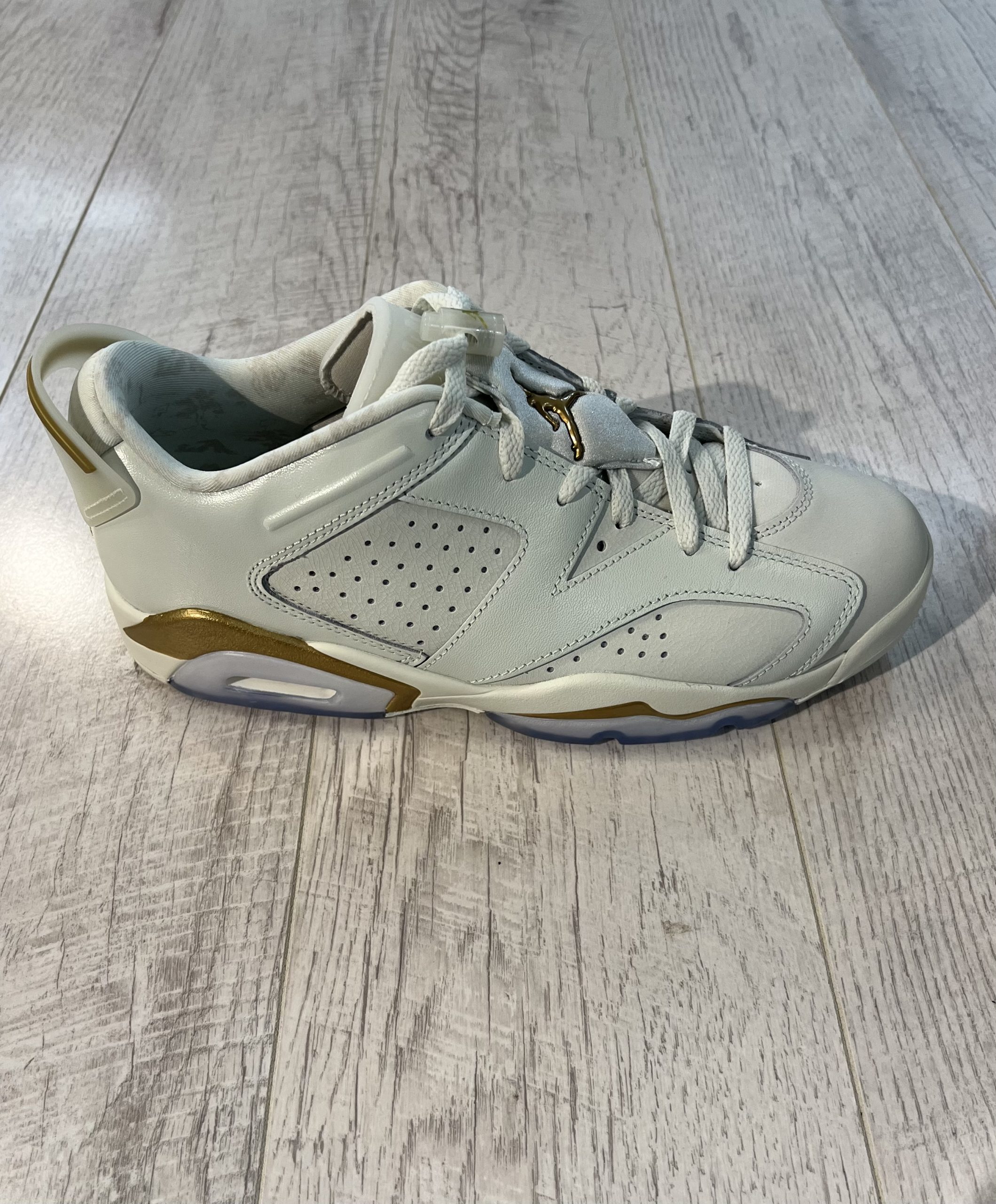 nike-air-jordan-6-low-chinese-new-year-2022.jpeg Vu de coté de la paire de Nike Air Jordan 6 Low Chinese New Year 2022. Un blanc couleur crème, des lacets blancs et du or sur le talon. Une matière en cuire.