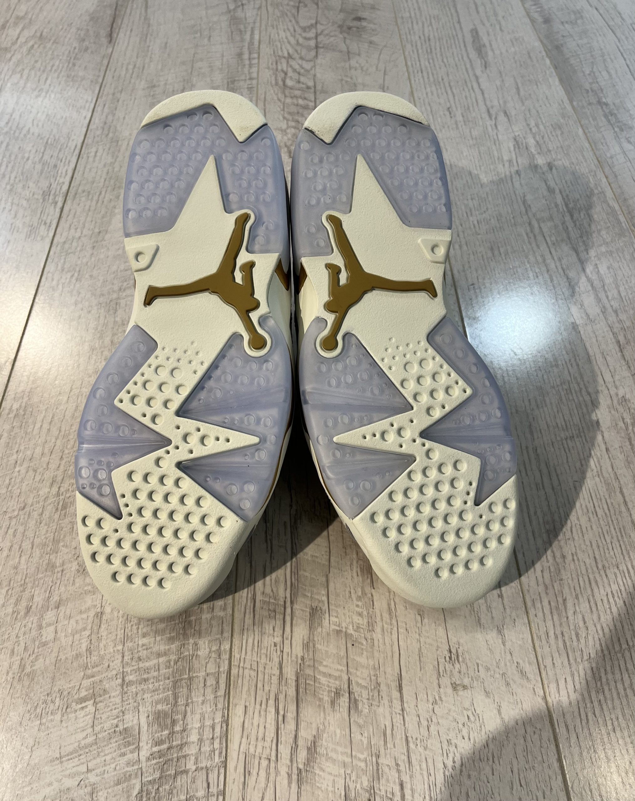 nike-air-jordan-6-low-chinese-new-year-2022.jpeg Vu du dessous de la Nike Air Jordan 6 Low Chinese New Year 2022. Du blanc et du bleu ciel transparent domient. Un logo Jordan doré est au milieu de la semelle.