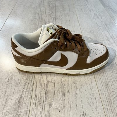 Vu de coté de la paire de Nike Dunk Low LX. Le marron domine le dessus de la paire. Du blanc est present. Les lacets sont marrons.