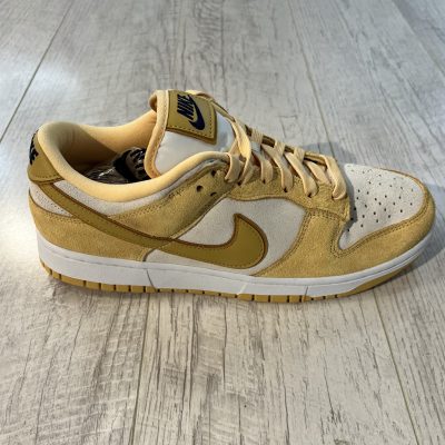Vu de coté de la paire de Nike Dunk Low Gold Suede. La couleur jaune pastel domine la paire ainsi que du blanc. Les lacets sont jaunes pastel.